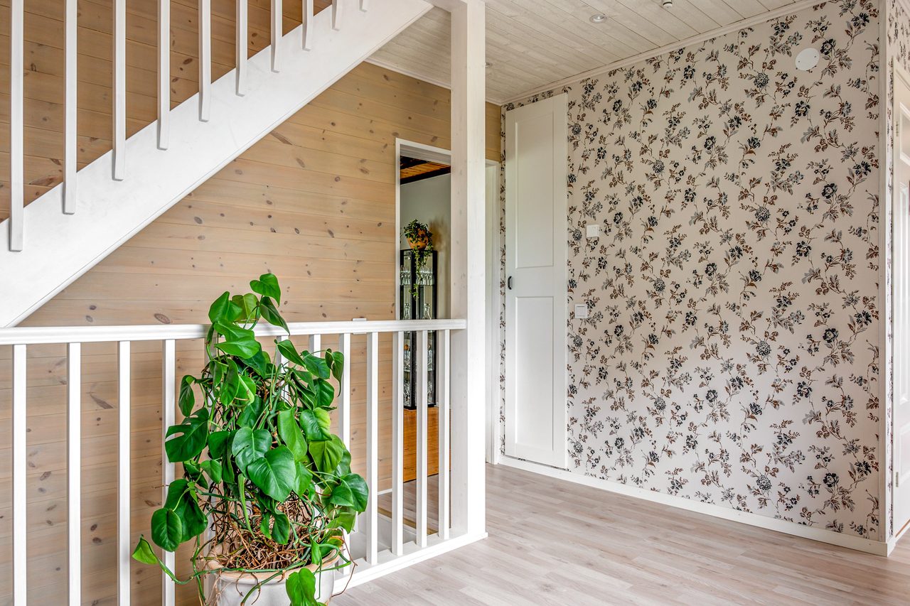 Rymlig hall med vitmålad trappa