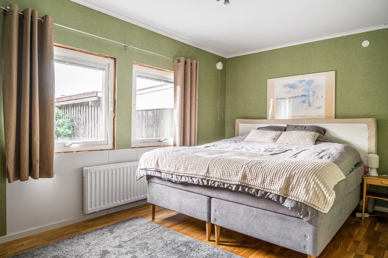 Stort sovrum som rymmer dubbelsäng och annat möblemang